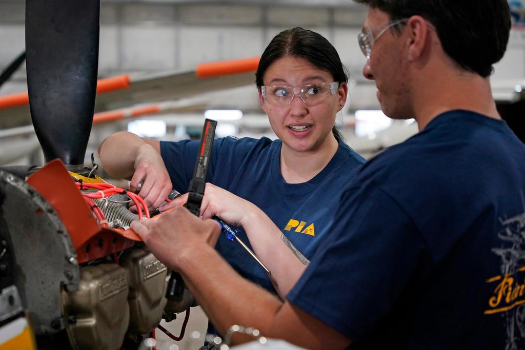 Students at the Pittsburgh Institute of Aeronautics Nikki Reed, center, and William Onderdork study the engine on an Cessna 310 aircraft in West Mifflin, Pa.