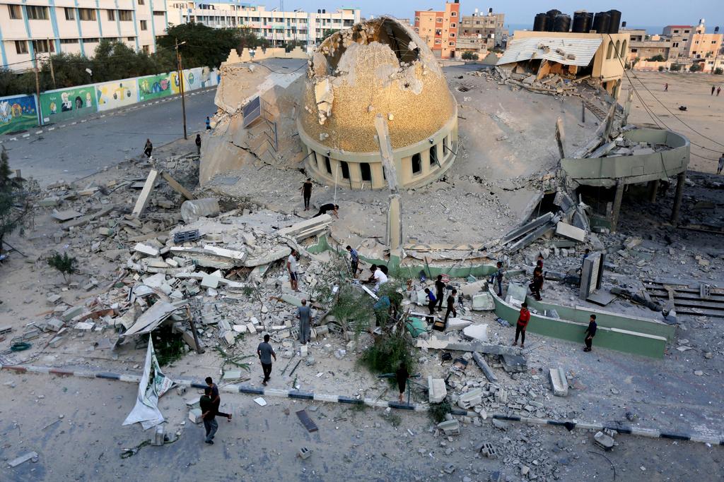 People stand outside a mosque destroyed in an Israeli air strike in Khan Younis, Gaza Strip