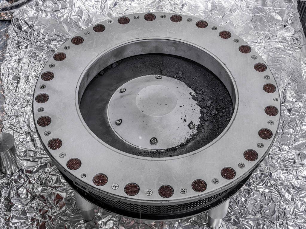 This photo provided by NASA on Wednesday, Oct. 11, 2023 shows the outside of the Osiris-Rex sample collector with material from asteroid Bennu at middle right. Scientists have found evidence of both carbon and water in initial analysis of this material. The bulk of the sample is located inside.