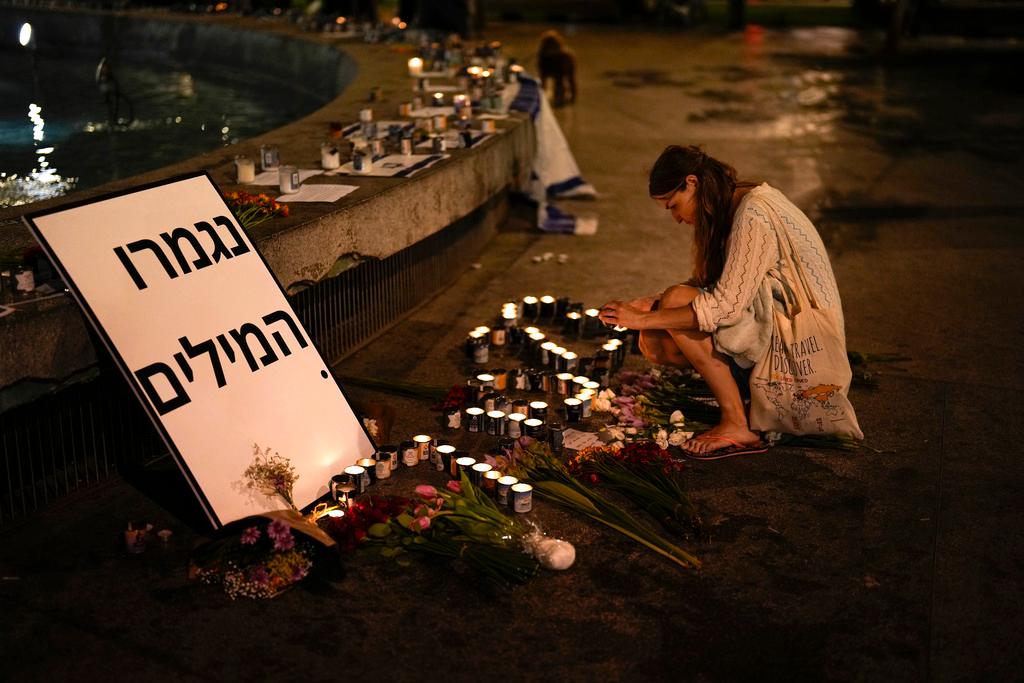 A woman lights candles in honor of victims of the Hamas attacks during a vigil at Dizengoff square in central Tel Aviv, Israel