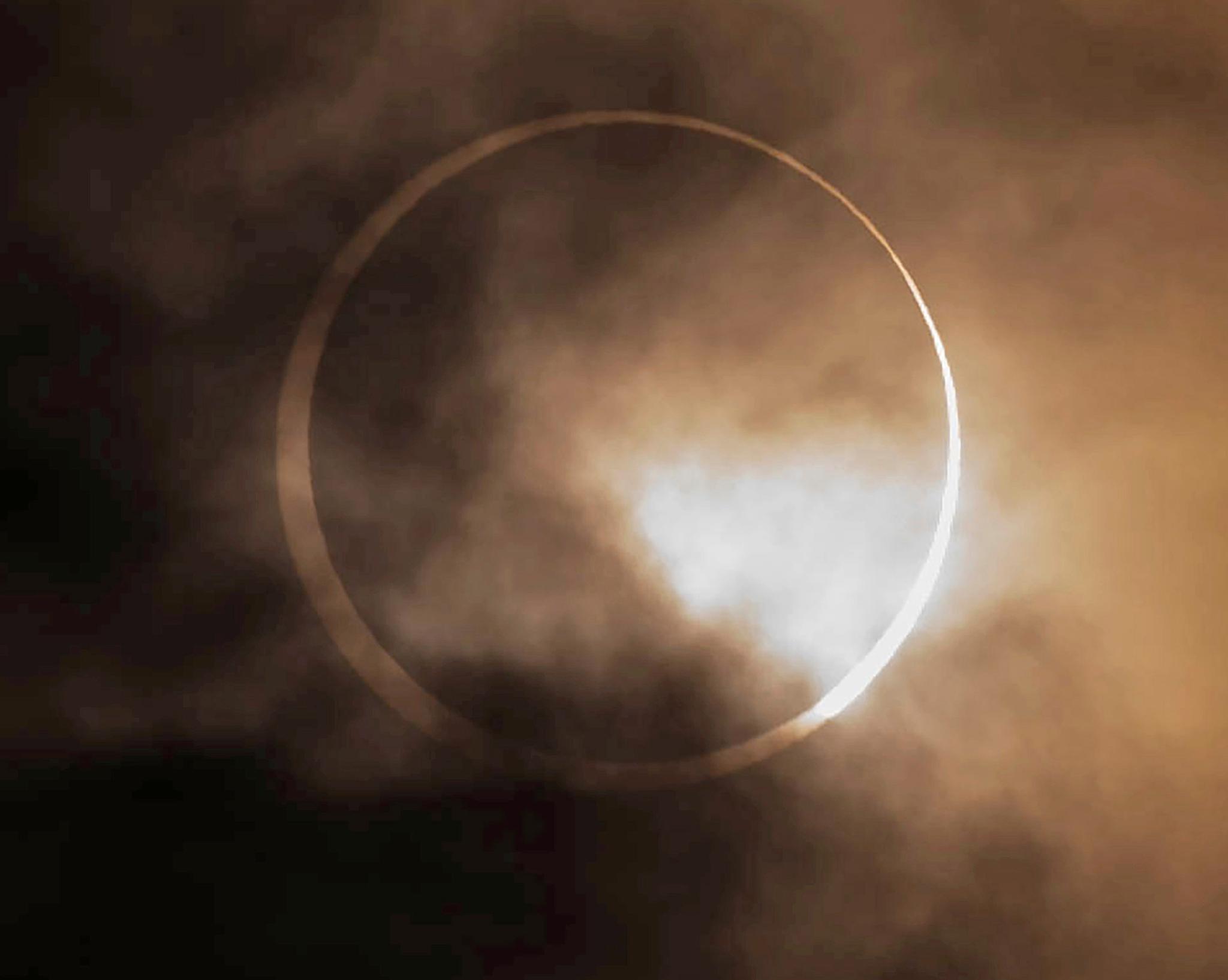 The annular solar eclipse appears from behind clouds above Skinner Butte in Eugene, Ore. Saturday, Oct. 14, 2023.