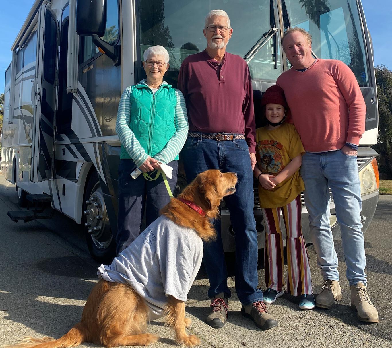 Woody, Luna and couple with their dog in front of a donated RV