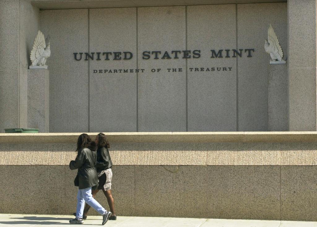 Two people walking past the United States Mint in Philadelphia