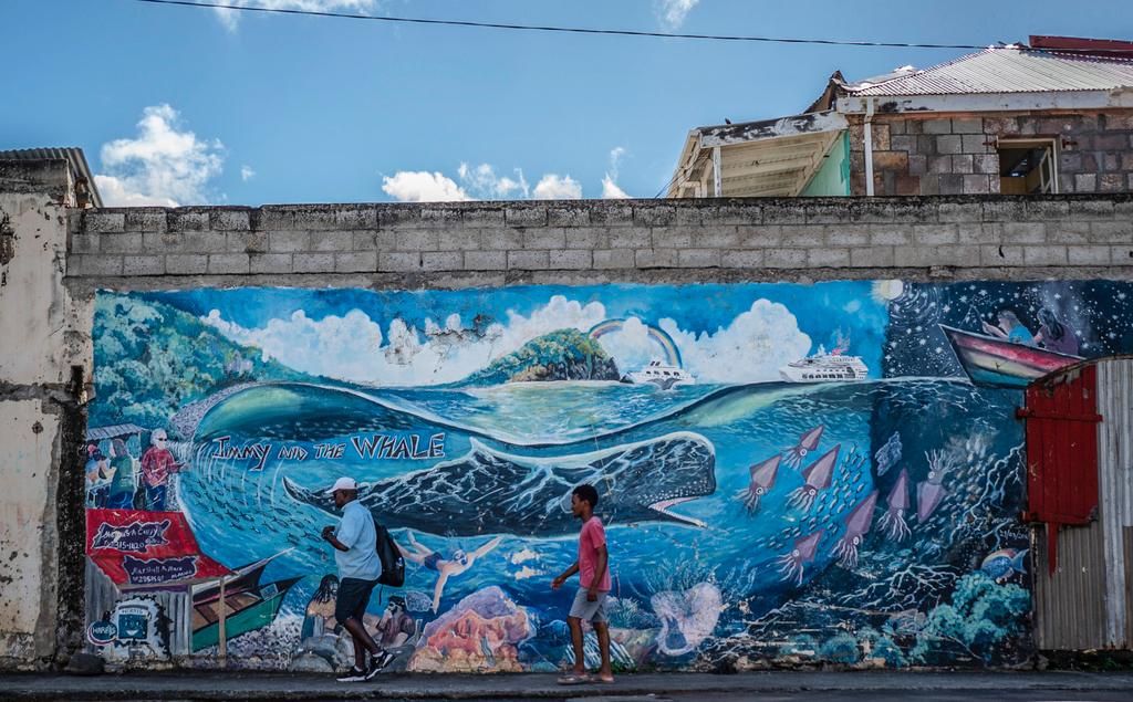 People walk past a mural of a whale created by artist Marcus Cuffi in Roseau, Dominica, Sunday, Nov. 12, 2023. The tiny island of Dominica announced on Nov. 13, 2023