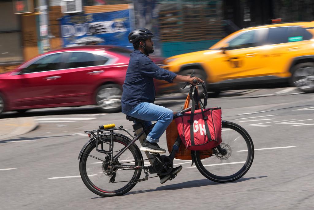 FILE - A delivery worker rides a motorized bicycle, July 25, 2023, in New York. On Monday, Nov. 13, New York City officials said that retailers and food delivery companies must do more to halt the proliferation of unsafe e-bike and e-scooter batteries after a fire blamed on an electric scooter's lithium ion battery killed three people over the weekend.