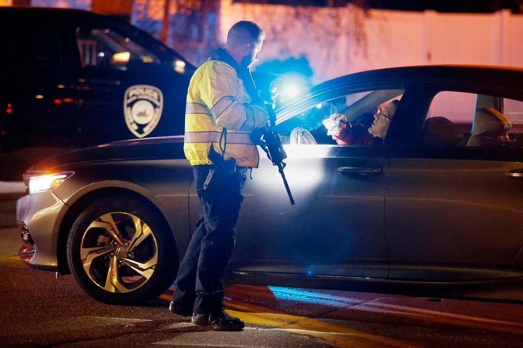 A police officer manning a roadblock talks with an employee of New Hampshire Hospital who was trying to get to work, Friday, Nov. 17, 2023, in Concord, N.H. 