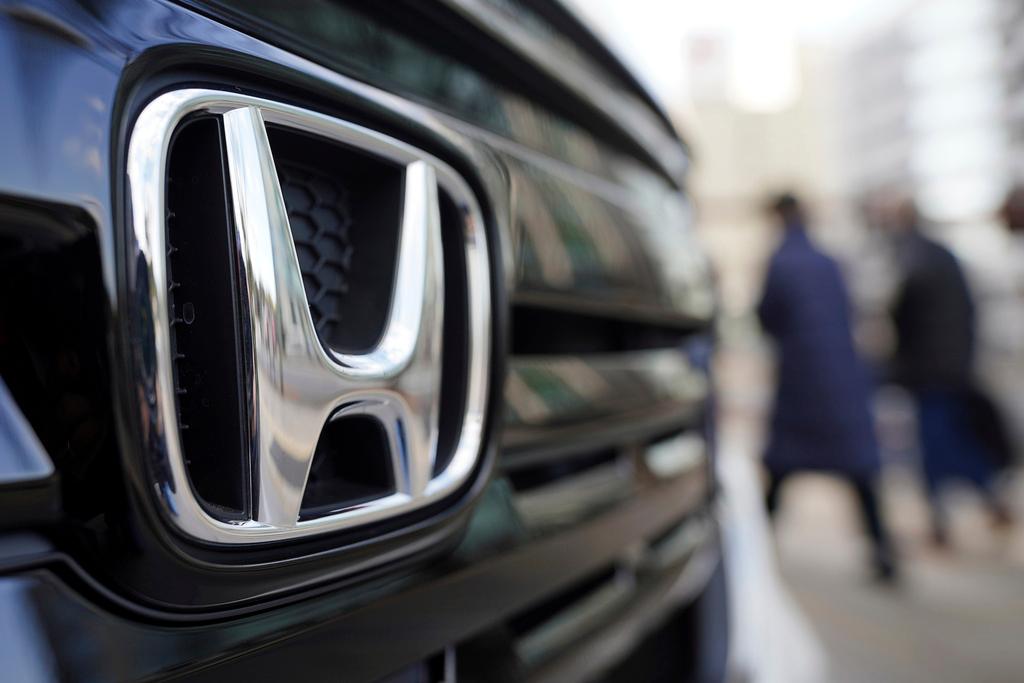 People walk near the logo of Honda Motor Company