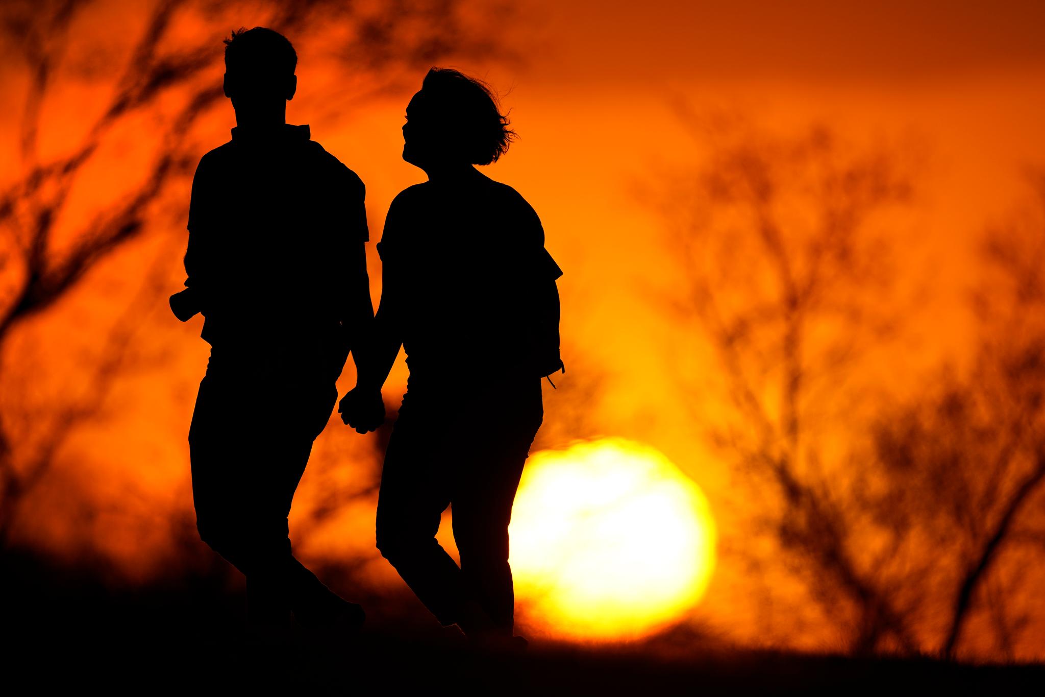 A couple walks through a park at sunset, March 10, 2021, in Kansas City, Mo.
