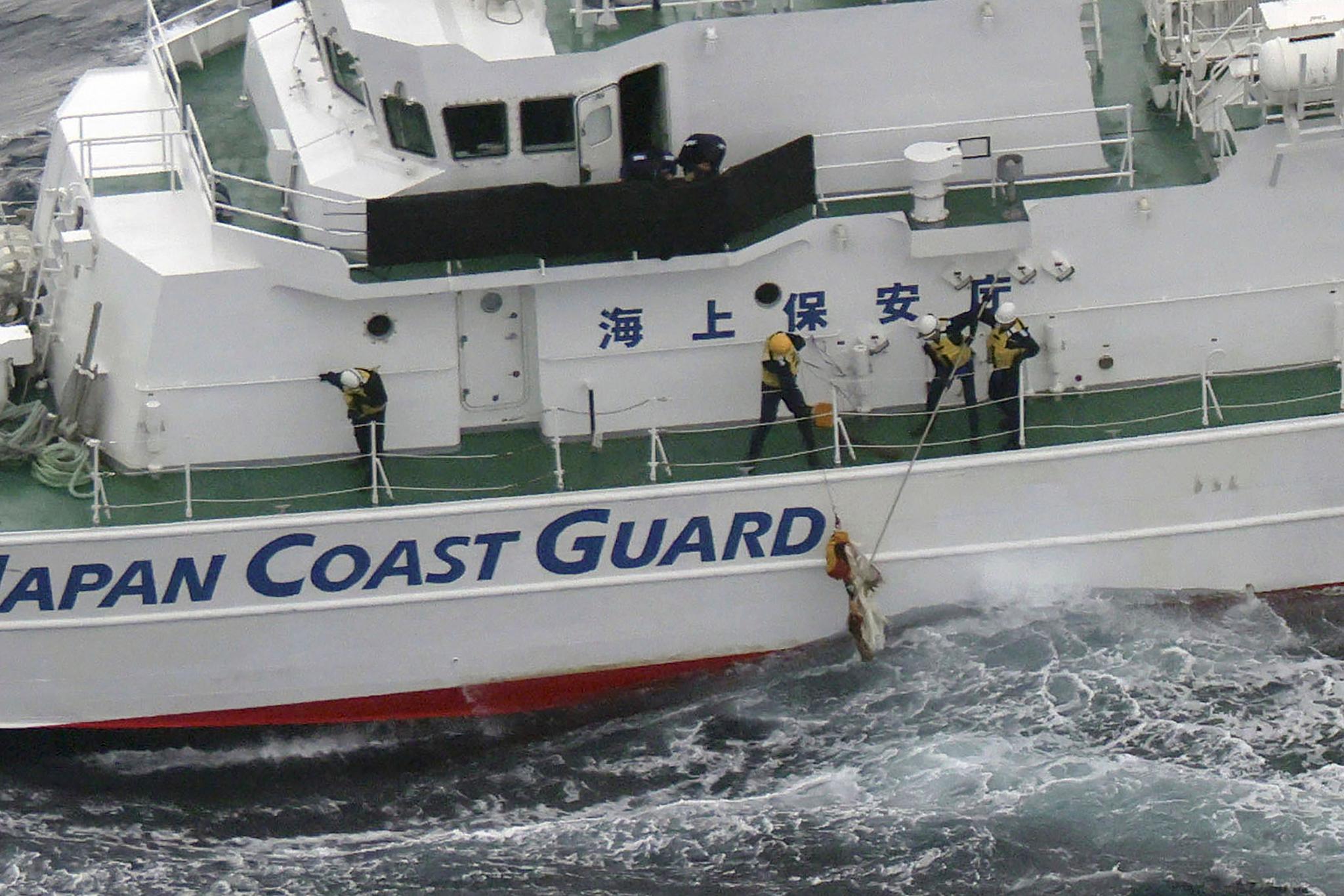 Japanese coast guard members pick up a floating object as they conduct search and rescue operation in the waters off Yakushima Island, Kagoshima prefecture, southern Japan Thursday, Nov. 30, 2023.