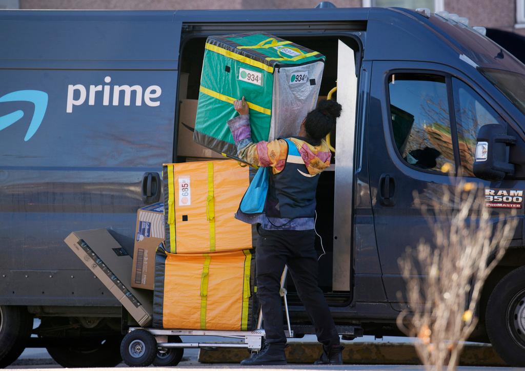 An Amazon Prime delivery person struggles with packages while making a stop at a high-rise apartment building 