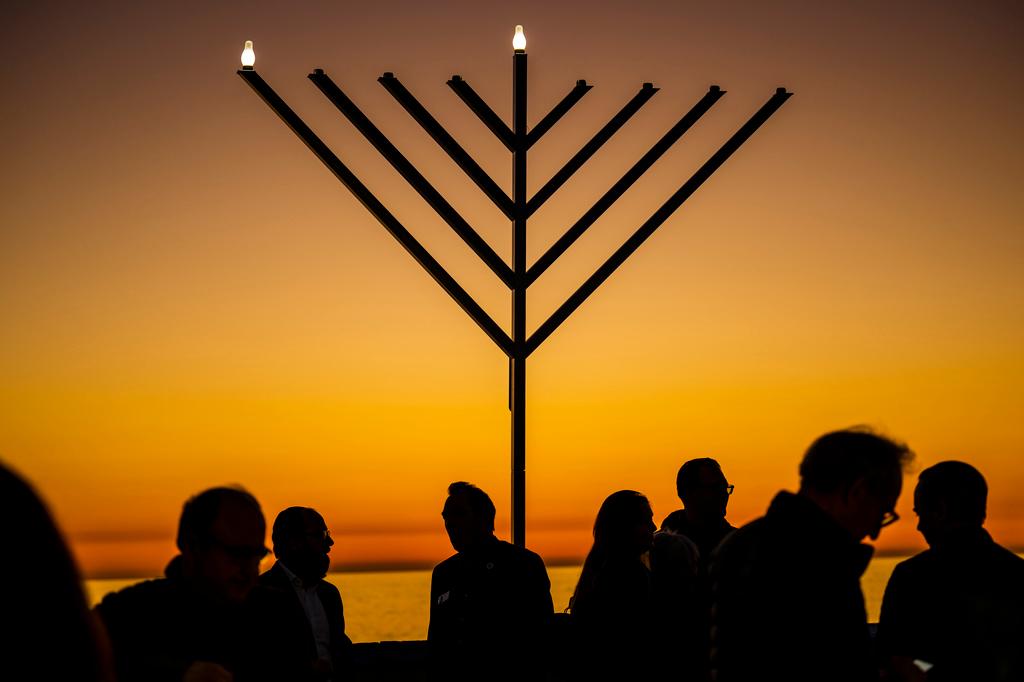 People gather around the 10-foot menorah during the "Hanukkah on the Pier" event at the end of the San Clemente pier hosted by Chabad of San Clemente in San Clemente, Calif.
