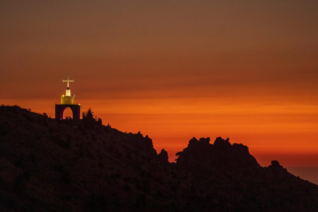 A Cross on a cliff overlooking the sunset over the scenic Kadisha Valley, a holy site for Lebanon's Maronite Christians, in the northeast mountain town of Bcharre, Lebanon, Friday, July 21, 2023.