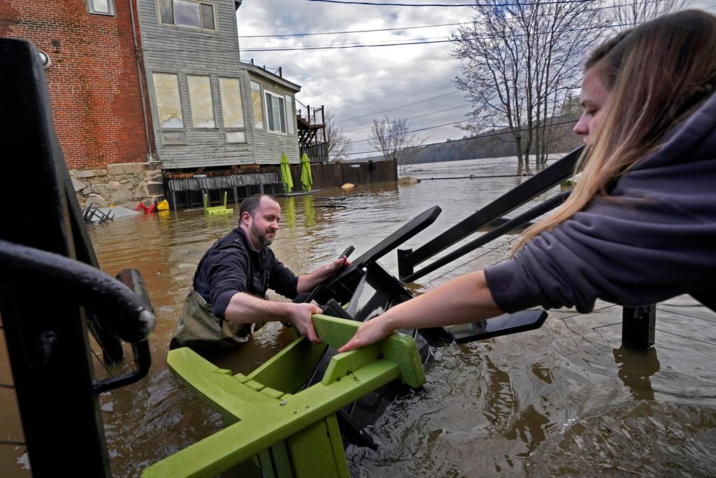 Man hands furniture to woman as they work in hip-deep water after storm
