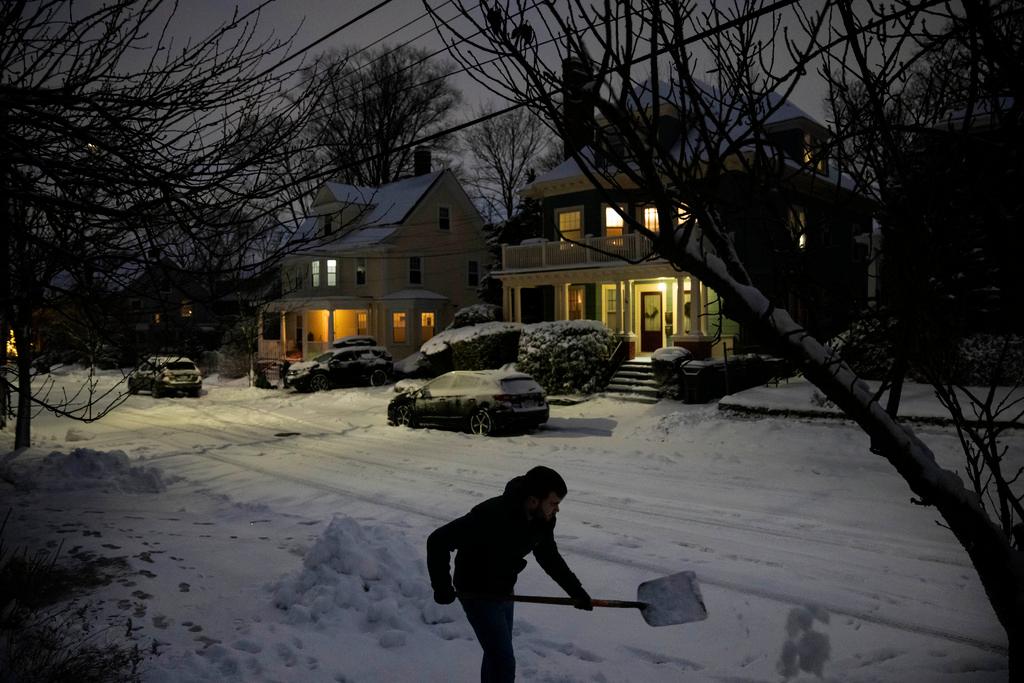 Colin Ladd clears snow from the sidewalk in front of his house in Providence, R.I. 