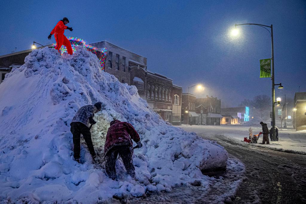 People stand on a large snow pile in Oskaloosa, Iowa