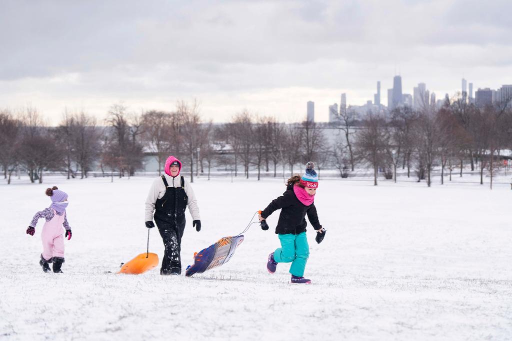 Kelly Schoenfelt, center, her daughter Quinlynn, left, 6, and Parker Melowsky, 7, run up Cricket Hill in the Uptwon neighborhood with sleds after a major snowstorm hit the Chicago area