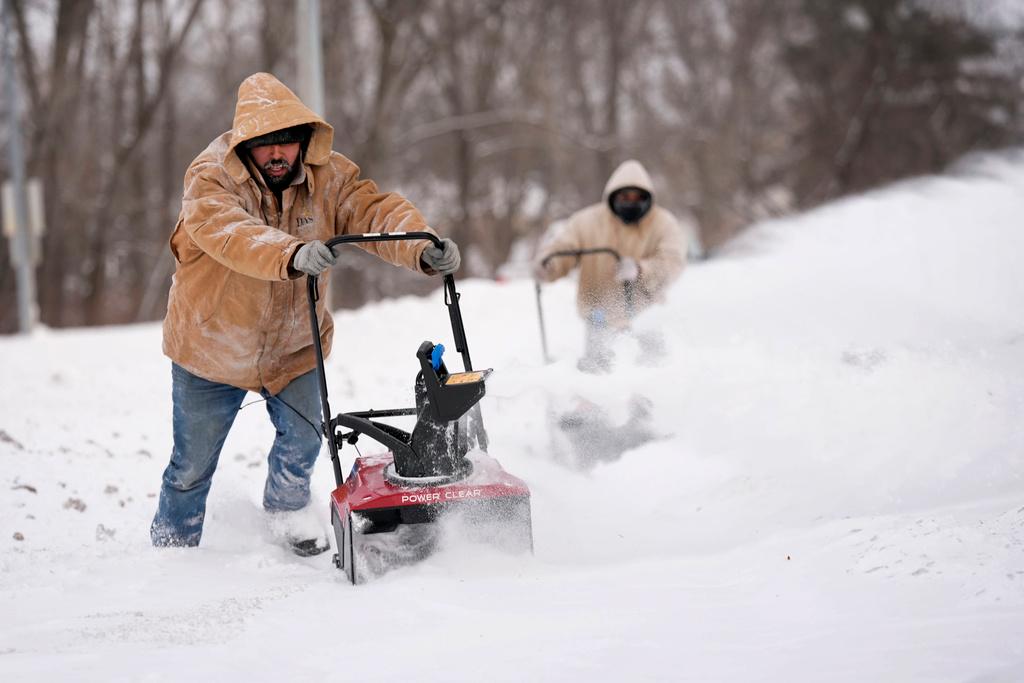 Workers clear a snow covered sidewalk