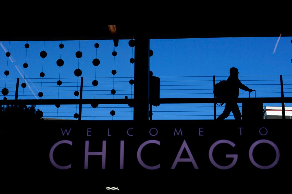 A passenger walks with luggage past holiday decorations at Chicago O'Hare International Airport