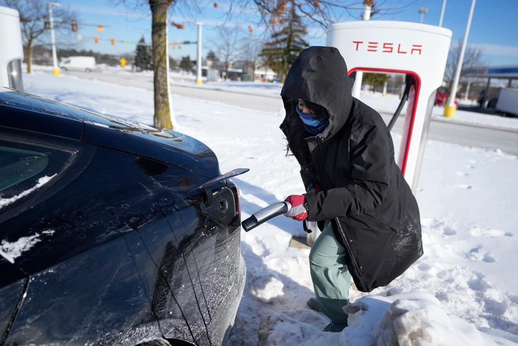 Woman prepares to charge electric vehicle at charging station