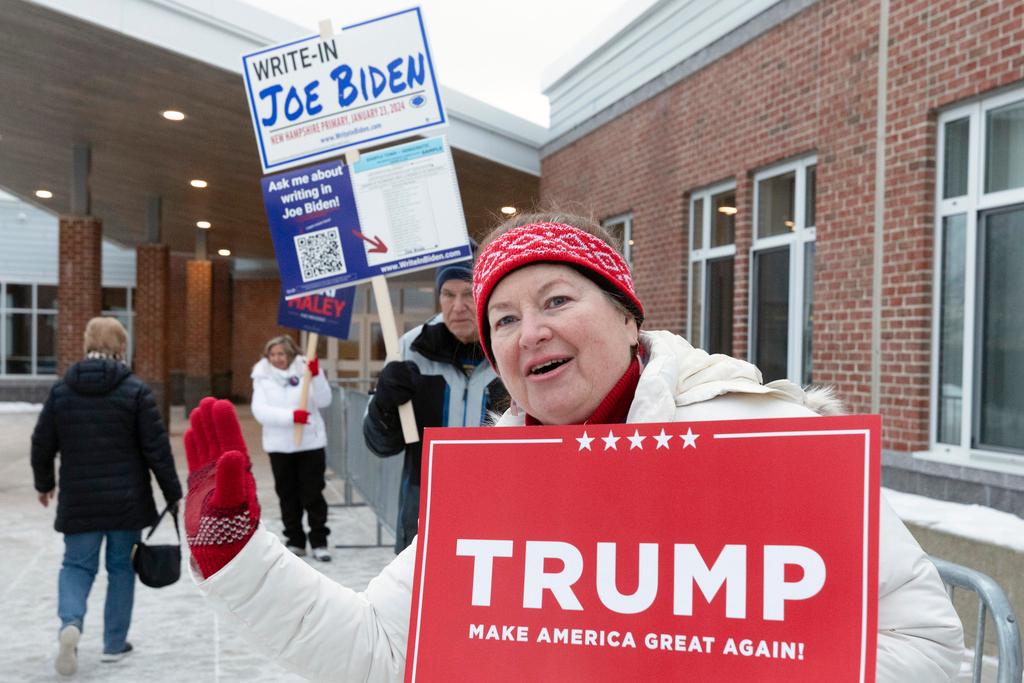 Voters hold candidate signs outside polling place in New Hampshire