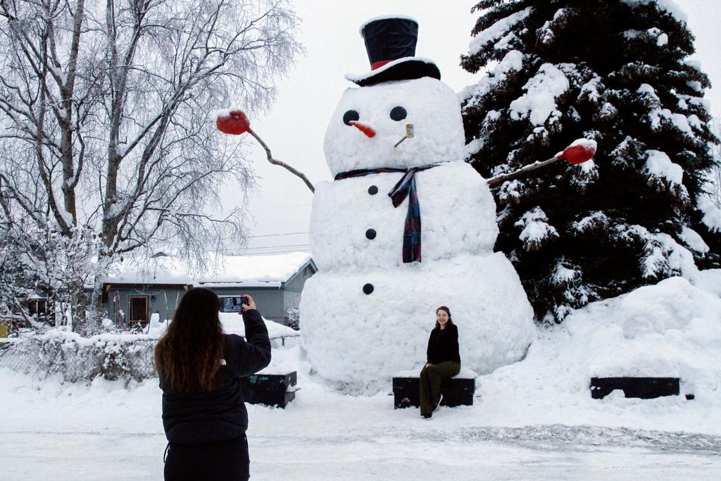 Isil Mico takes a photo of her sister-in-law Oznur Mico in front of Snowzilla, a snowman measuring more than 20 feet tall, in Anchorage, Alaska on Jan. 10, 2024.