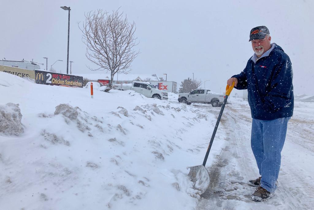 Man with shovel stands by side of the road covered with snow