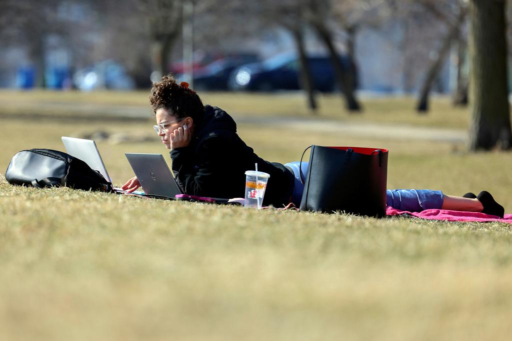 Tania Sepulveda takes advantage of the warmer than normal temperatures to work on her laptop computer outside her home near Montrose Harbor in Chicago