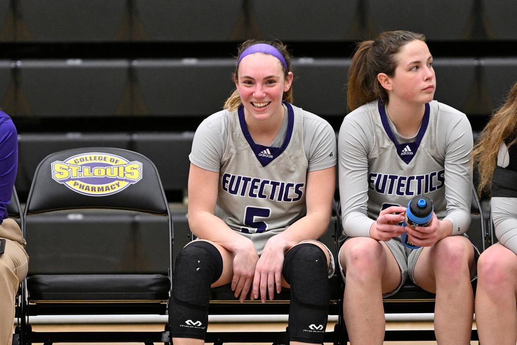 University Health Sciences and Pharmacy guard Grace Beyer (5) smiles on the bench during an NAIA college basketball game against Cottey College in St. Louis