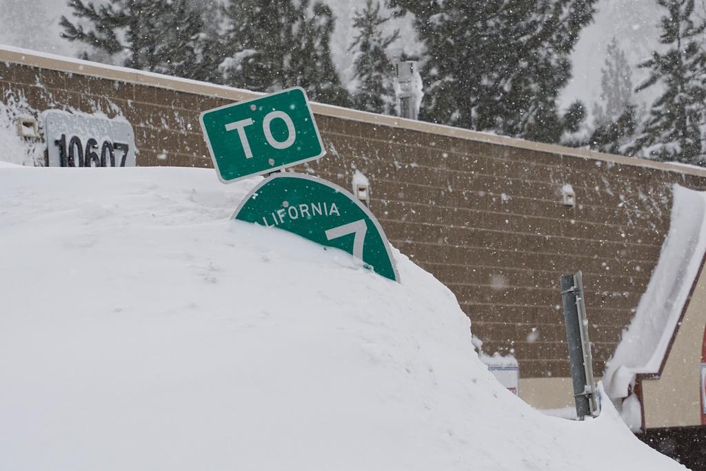 A highway sign is covered in snow during a storm, Sunday, March 3, 2024, in Truckee, Calif.