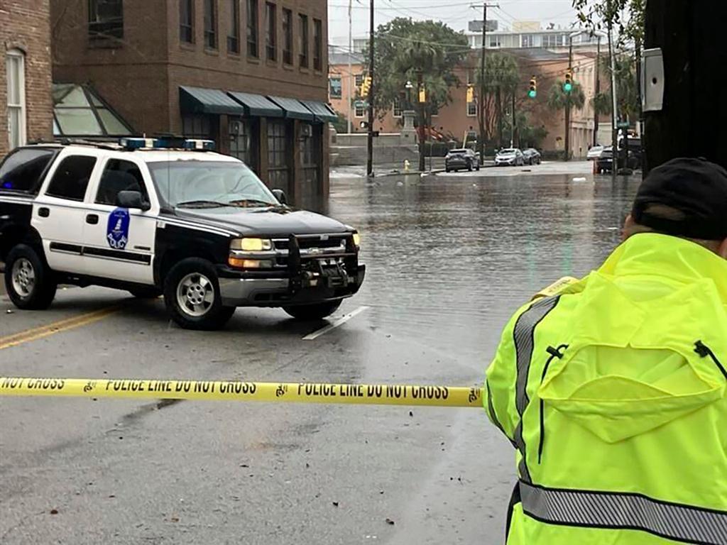Charleston police officer closes off a portion of Market Street during heavy rains and flooding 