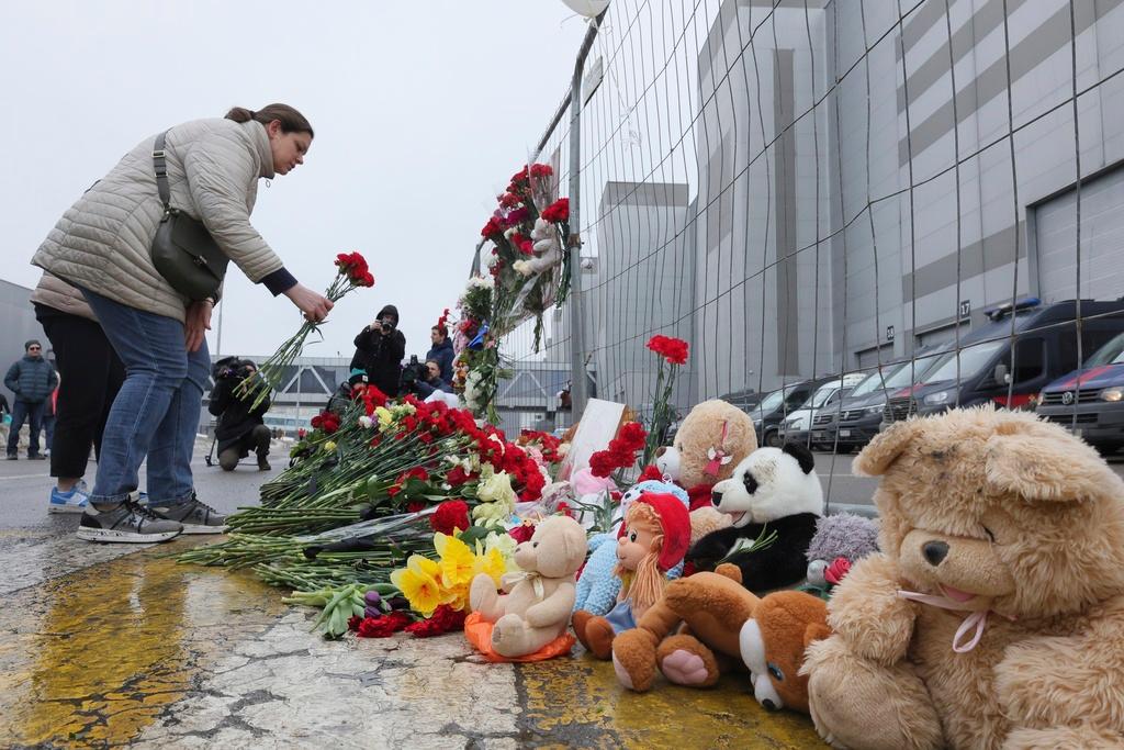 Woman places flowers by the fence next to the Crocus City Hall, on the western edge of Moscow