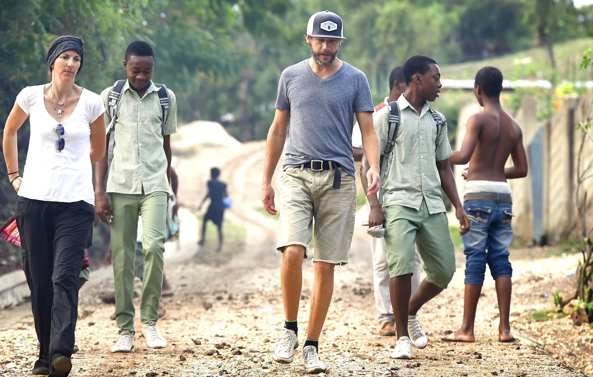 Woman and several men walking on a dirt road