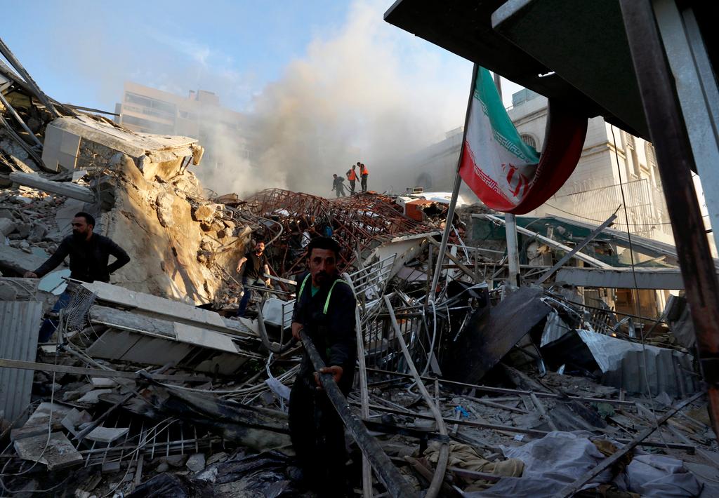Emergency services work at a building hit by an air strike in Damascus, Syria