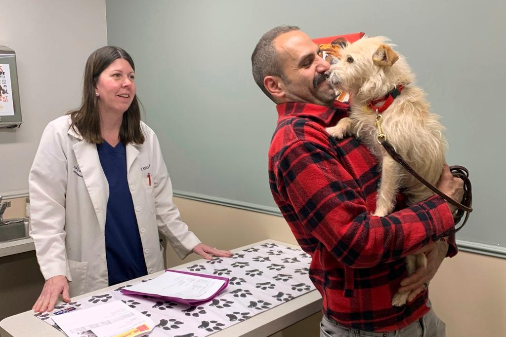 Mehrad Houman holds his dog, Mishka, after she was examined by veterinarian Nancy Pillsbury in Harper Woods, Mich.
