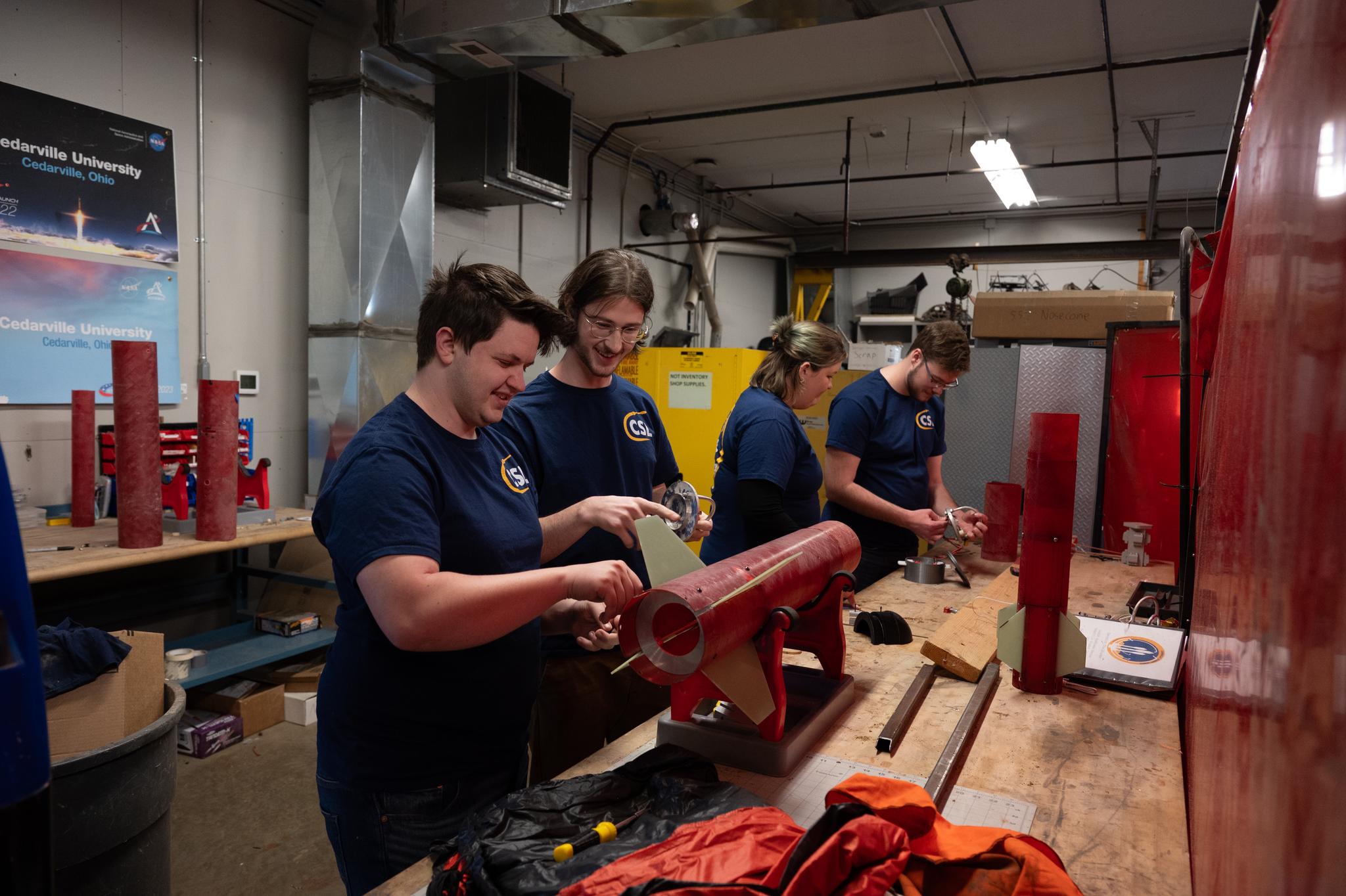 Drake Beckloff, Cade Gehman, Ginny Clark, and Christopher Needham work on their rocket prototype in the lab.