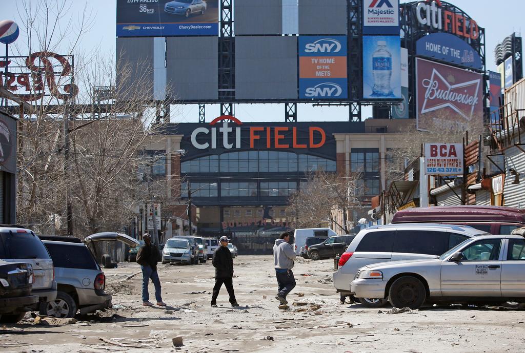  Workers cross an unpaved street adjacent to Citi Field, home to the New York Mets baseball team