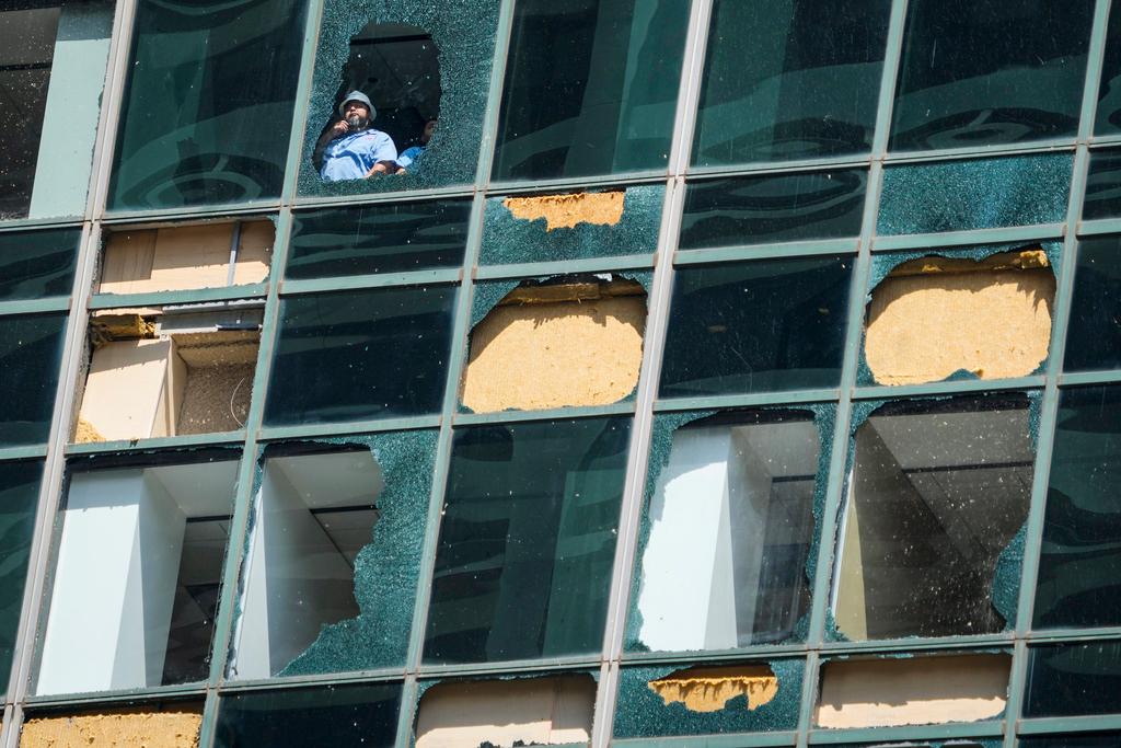 Workers clean out shattered glass of building