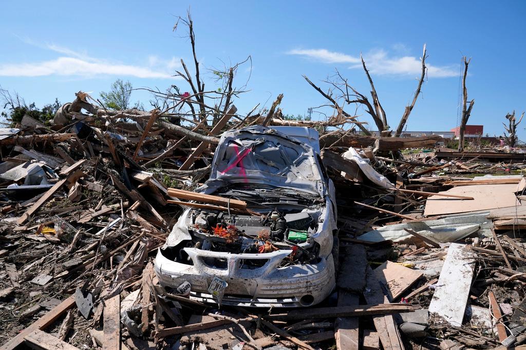 Tornado damaged car sits in a pile of debris