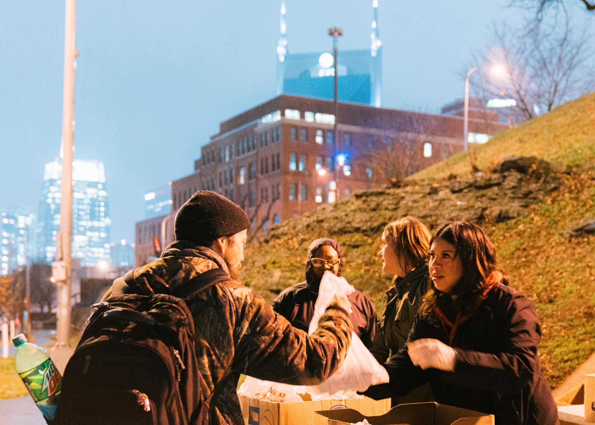 Woman handing man a bag of food with city skyline in the background
