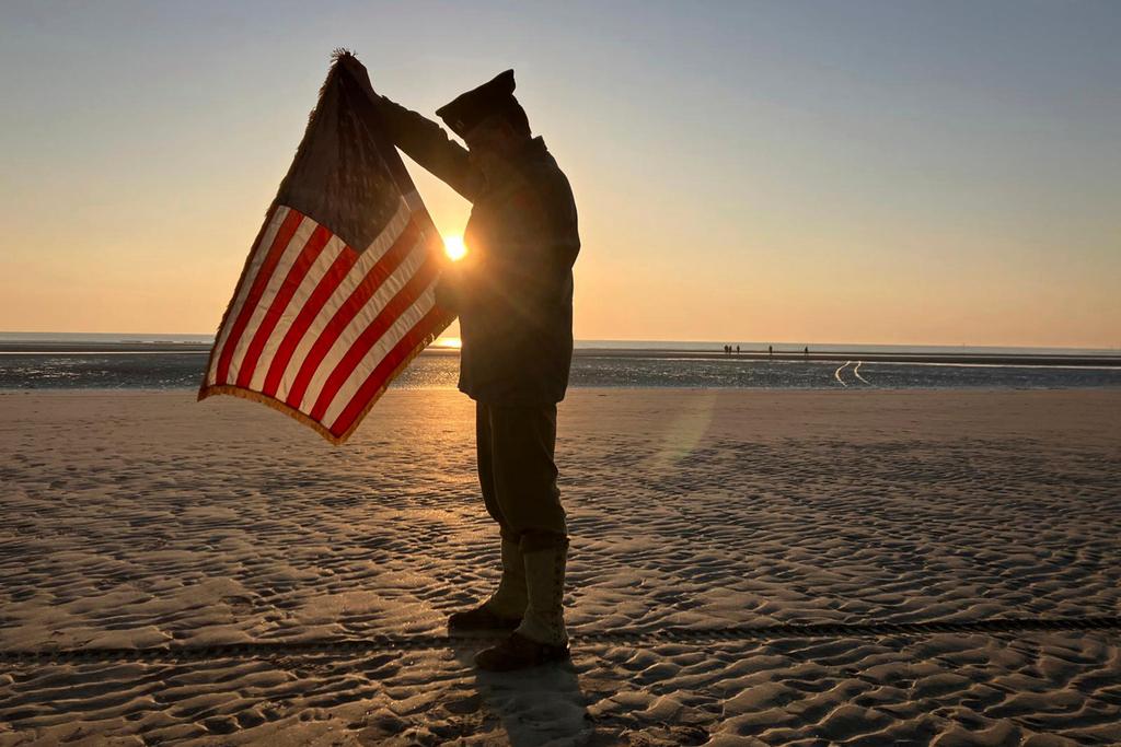 Christophe Receveur, of France, unfurls an American flag he bought six month ago in Gettysburg, Penn., to mark D-Day, Thursday, June 6, 2024 on Utah Beach, Normandy.
