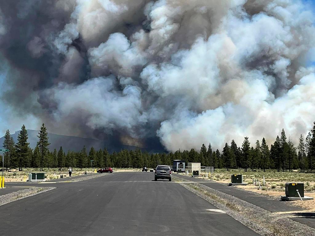 Smoke from a wildfire rises on a road near La Pine, Ore., Tuesday, June 25, 2024.
