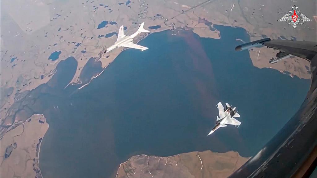 A H-6K long-range bomber of the Chinese air force, upper left, is seen escorted by a Su-30 fighter of the Russian air force during a joint Russia-China air patrol
