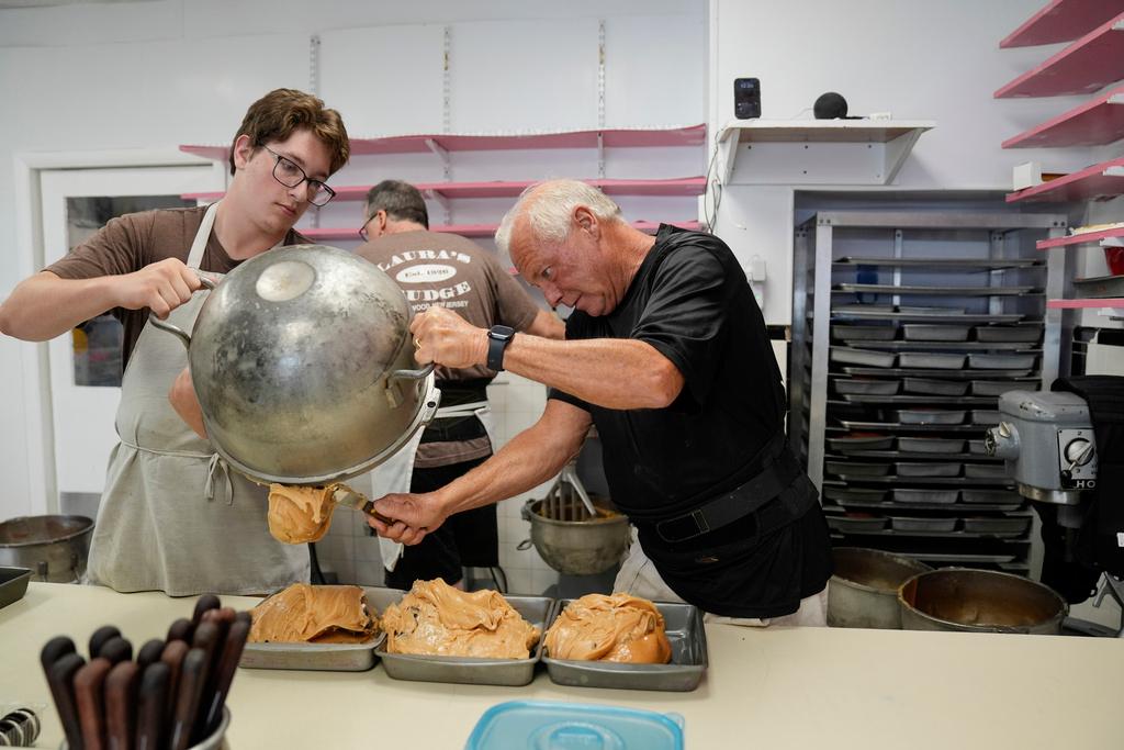 Sean Wood, left, helps as Dave Roach, owner of Laura's Fudge, scoops fudge into a pan at his store in Wildwood, N.J.