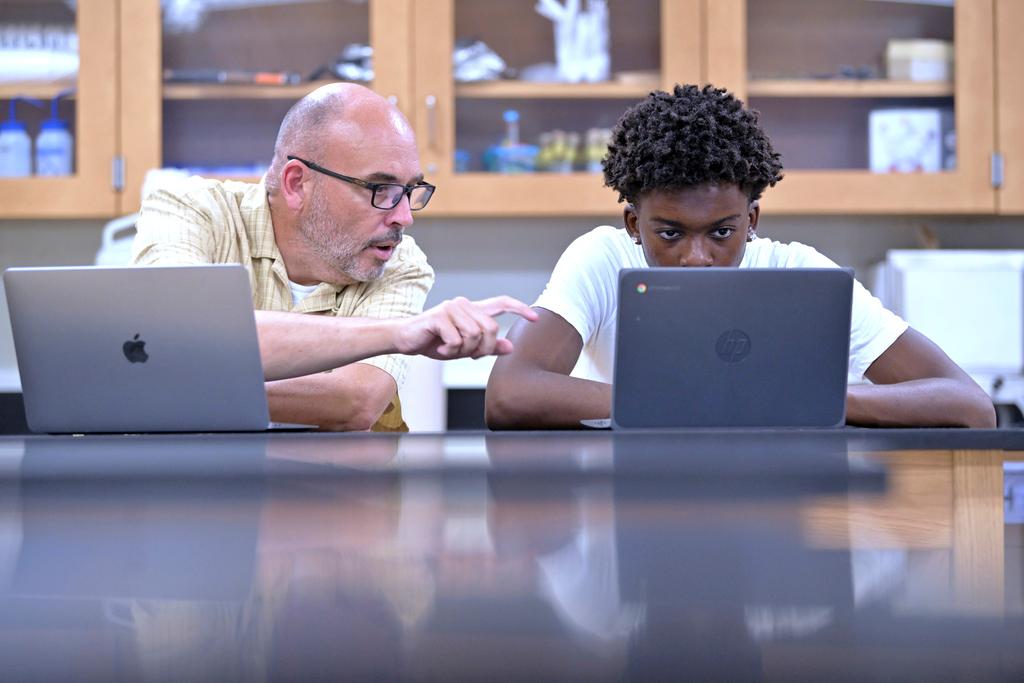 History teacher Matt Brophy, left, works with Flerentin “Flex” Jean-Baptiste, 16, of Medford, Mass., on making up late assignments during summer school 