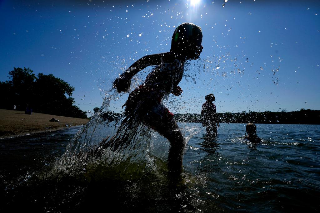 Judah Boyle, of Des Moines, Iowa, splashes water as he runs on the beach at Gray's Lake Park in Des Moines, Iowa