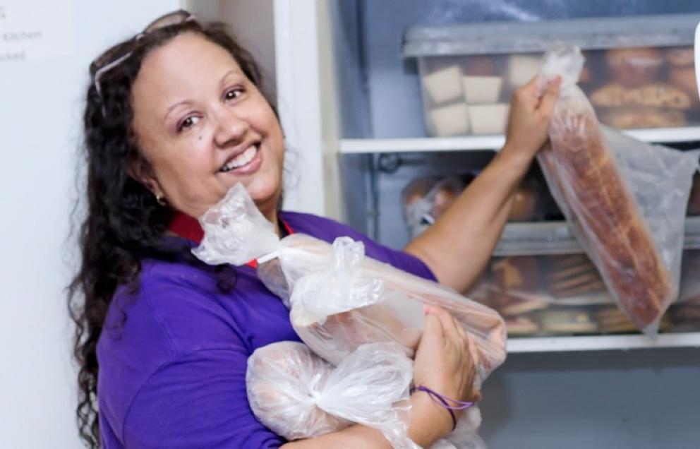 Woman in purple handling loaves of bread