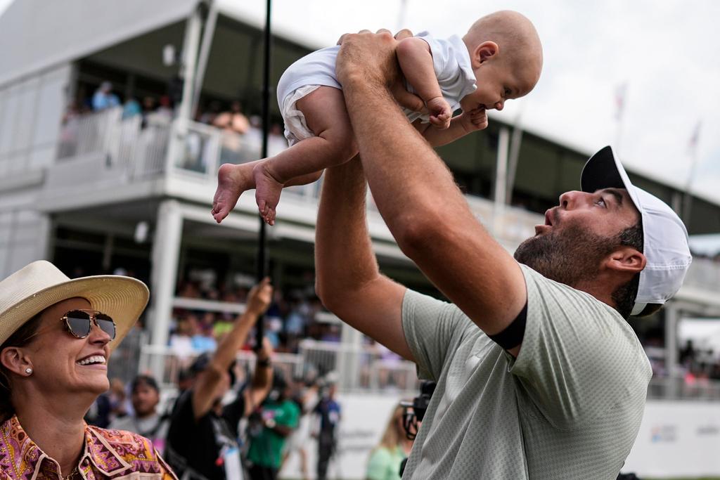 Scottie Scheffler holds his son Bennett Ezra Scheffler as his wife Meredith Scudder looks on the 18th green after Scheffler won the final round of the Tour Championship golf tournament, Sunday, Sept. 1