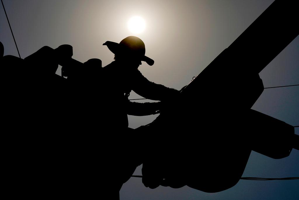 A lineman works on power lines under the morning sun in Phoenix