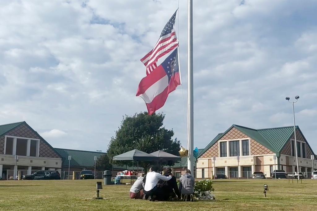 People gather at the flagpole outside the entrance to Apalachee High School a day after deadly shootings