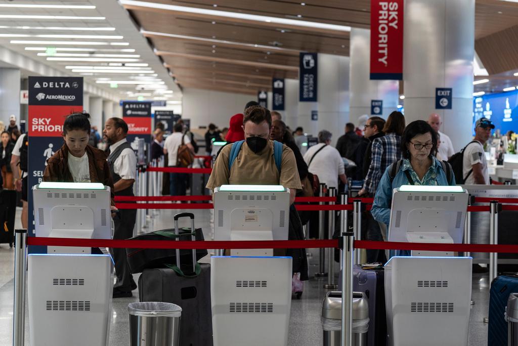 Travelers use kiosks to check in for flights in the Delta Airlines ticketing area 